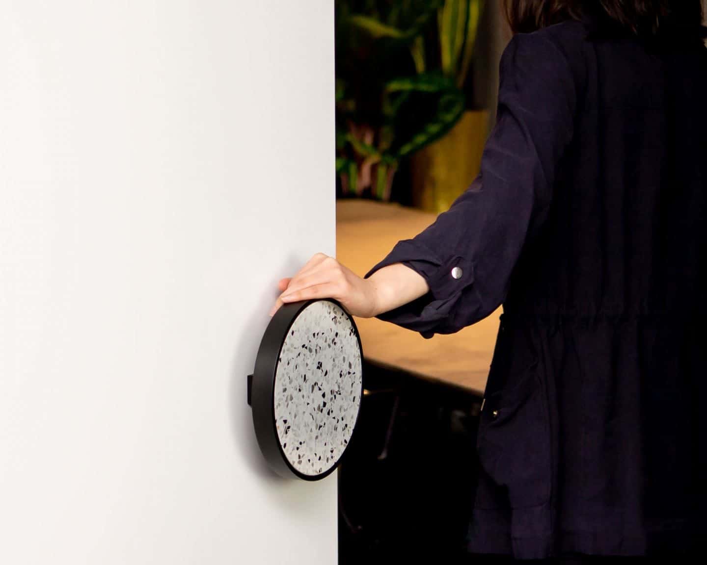 Lady opening a terrazzo designer door handle from Designer Doorware