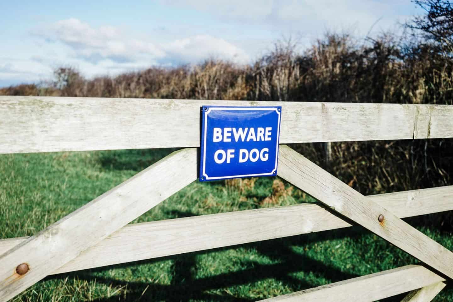 Beware of dog enamel signs from Ramsign seen on a gate in a field 