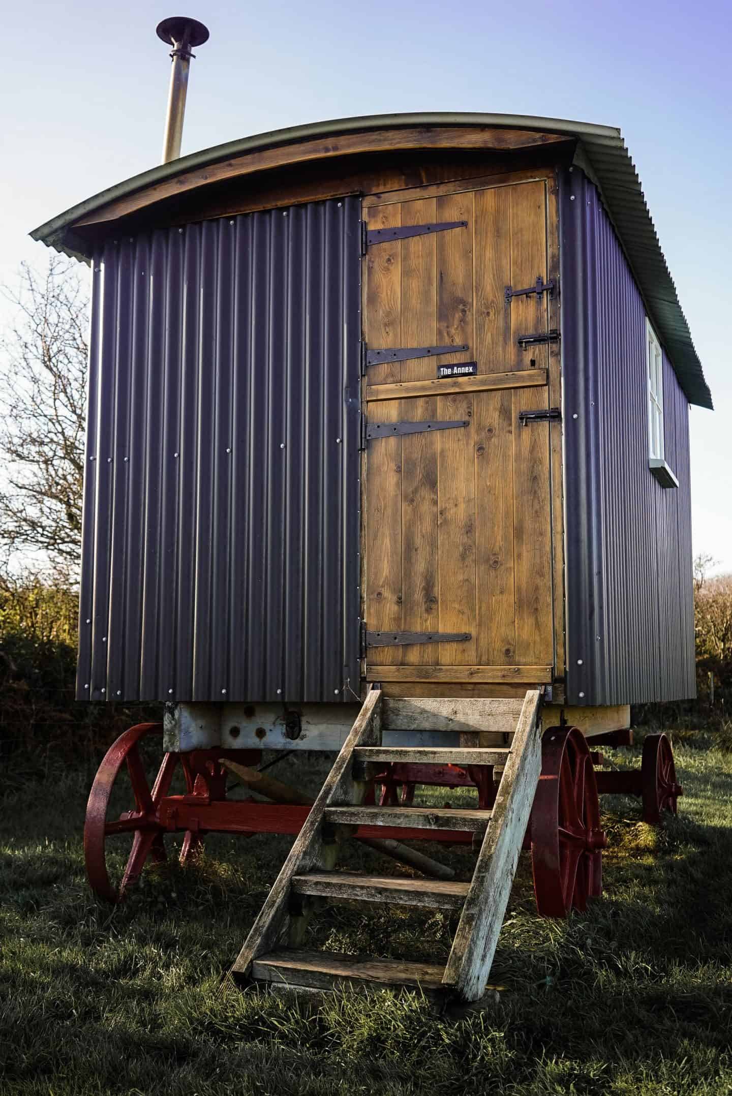 Traditional British shepherd's hut featuring an enamel sign