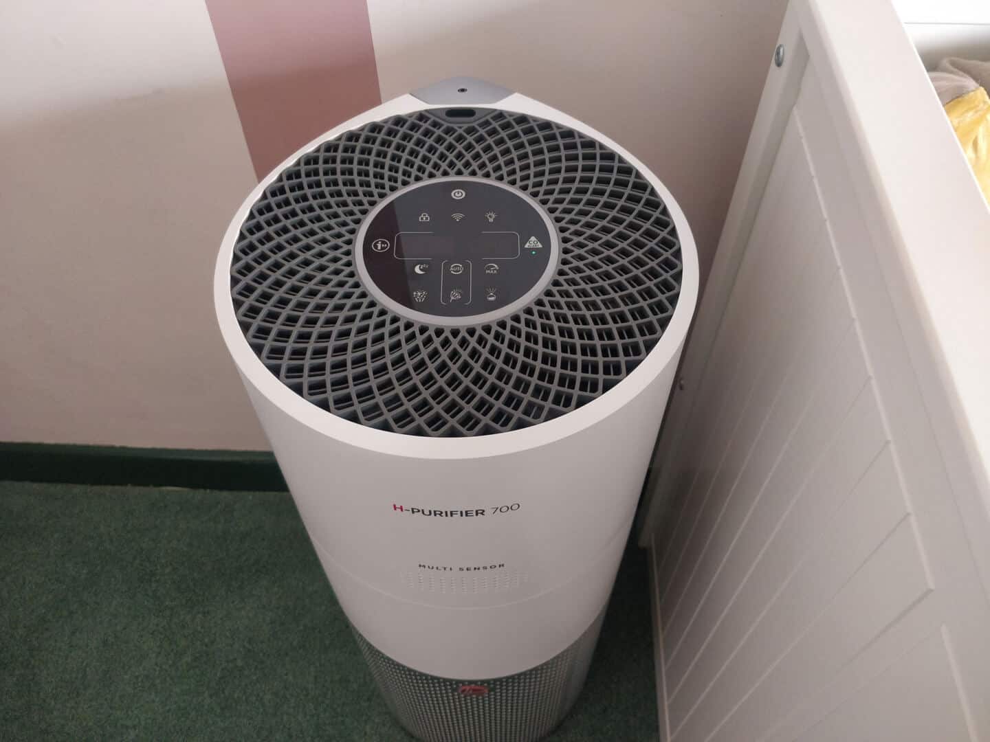 The Hoover Air Purifier 700 stands next to a day bed in a bedroom.