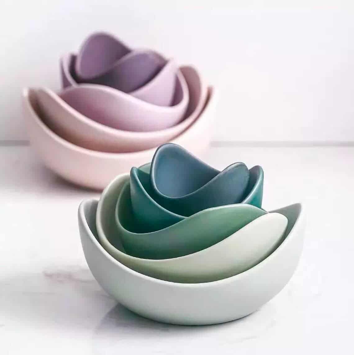 A stack of green ceramic bowls with a stack of pink ceramic bowls behind