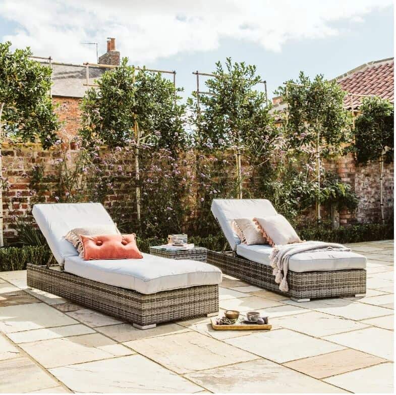 Two garden sunloungers on a patio with trees behind