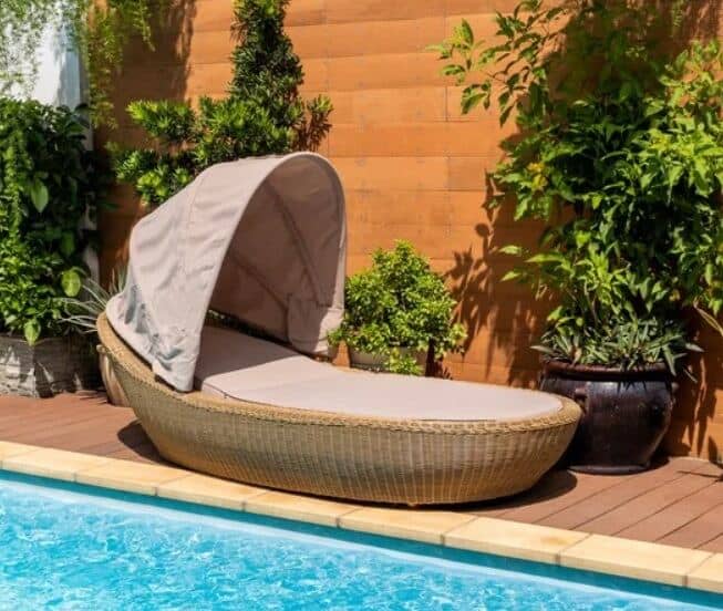 a day bed with canopy next to a swimming pool 