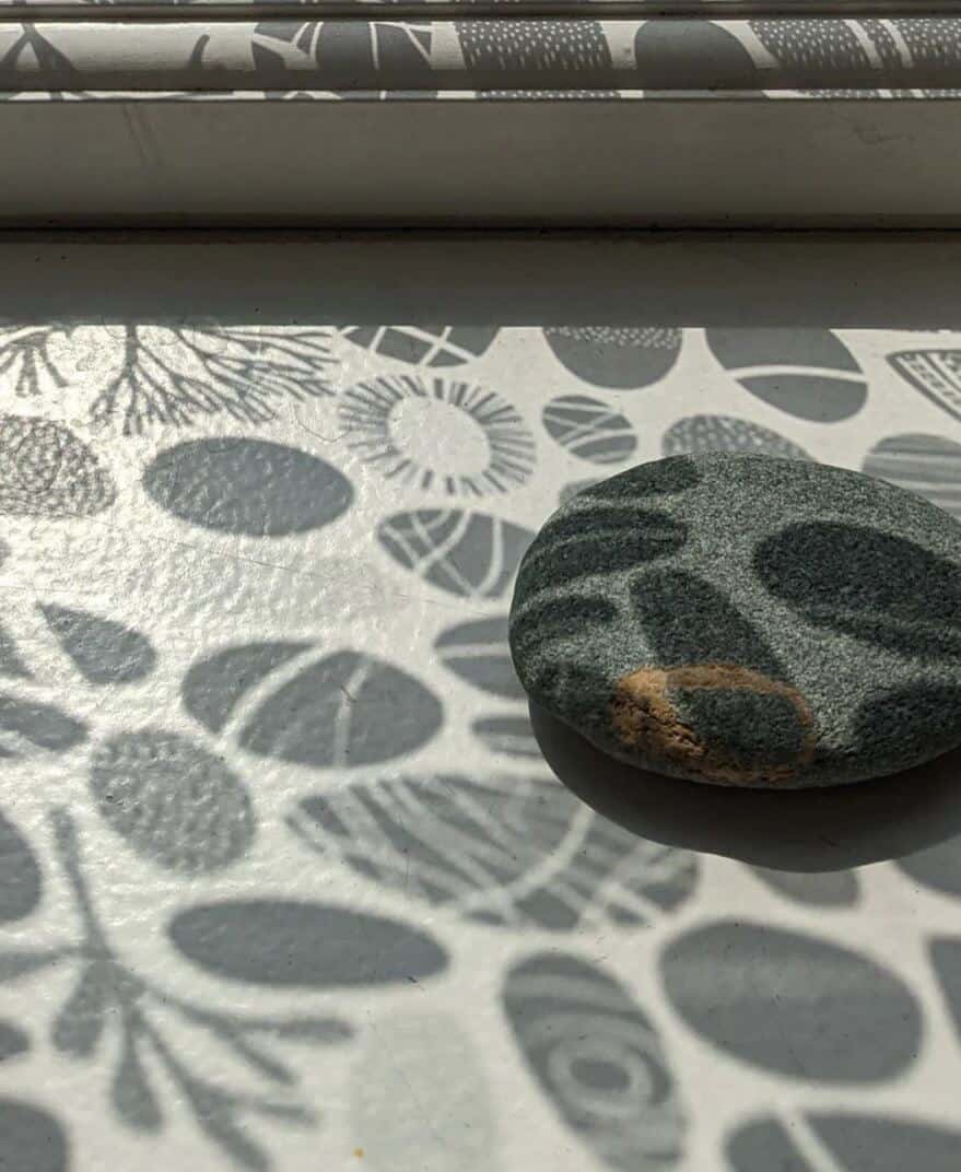 shadows cast on the window sill of pebbles created by the sunlight coming through the window film