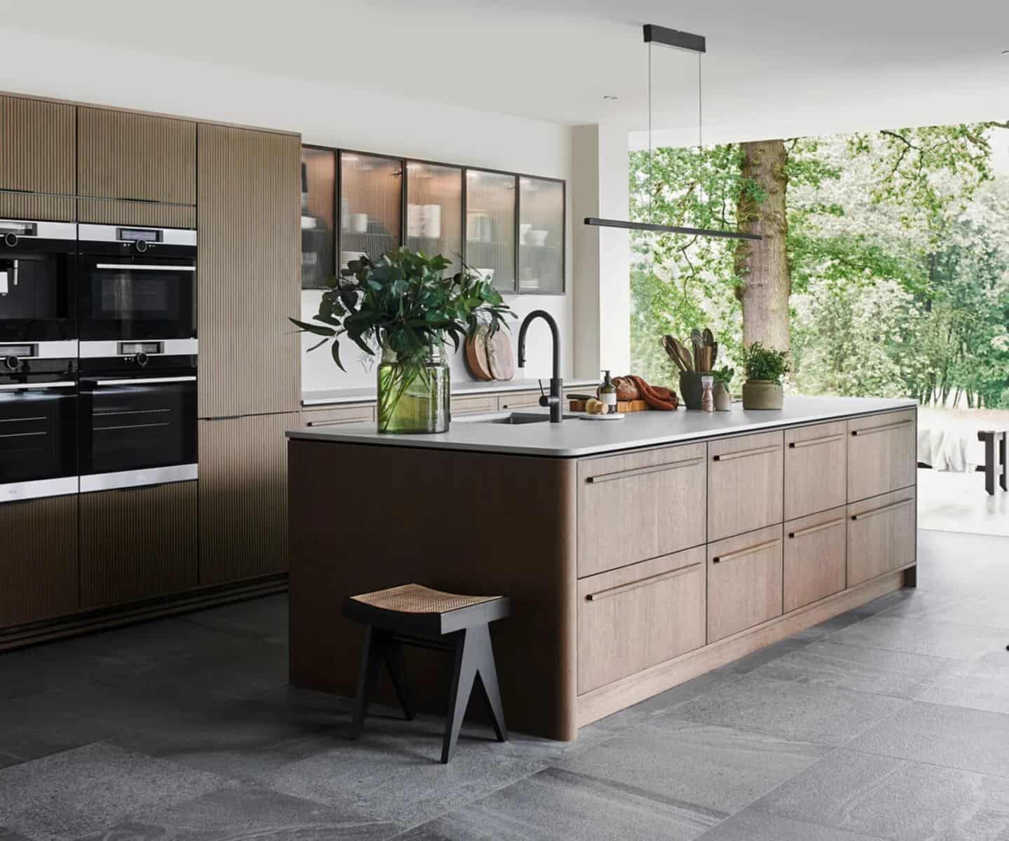 A wooden kitchen with island overlooking a leafy garden