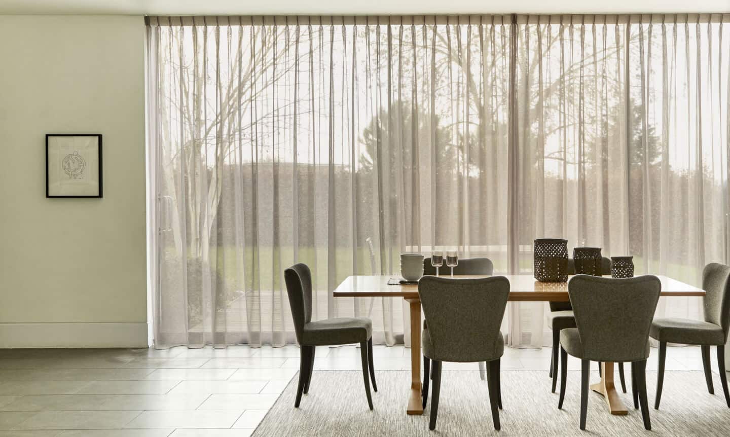 Floor to ceiling floaty voile curtains cover the windows in this dining room