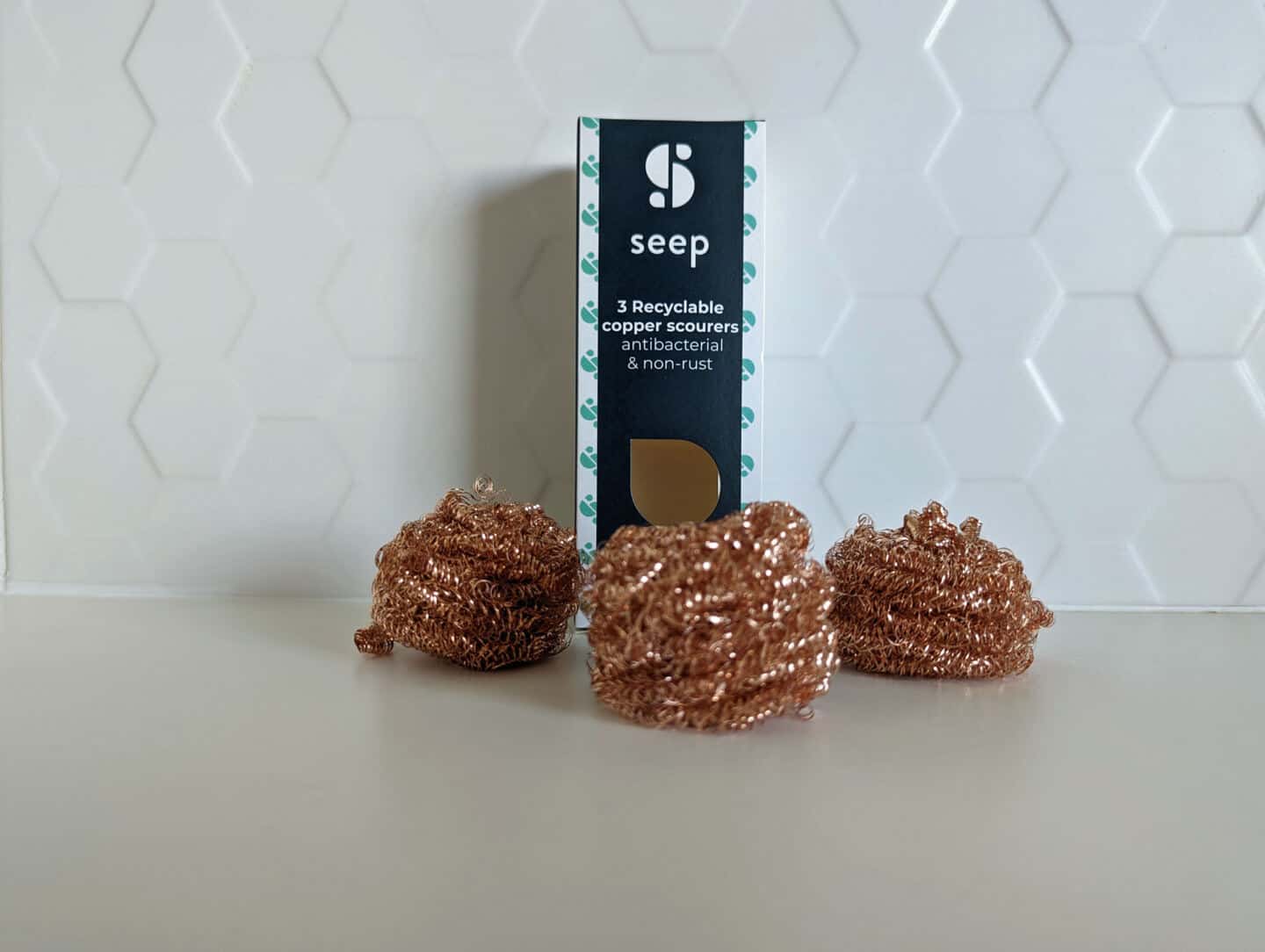 3 recyclable copper scourers from Seep on a white worktop with white tiles behind