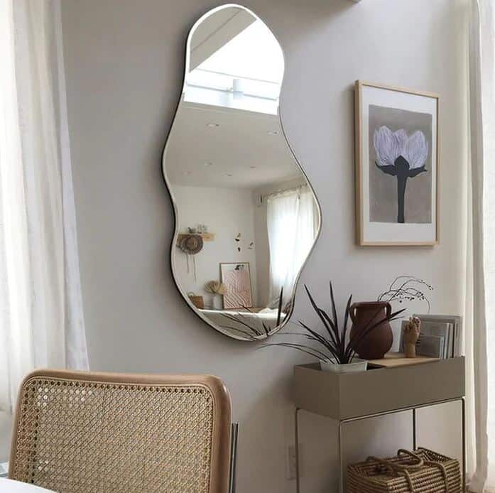 An organic shaped wall-mounted mirror from Neutypechic above a Scandi-style storage unit