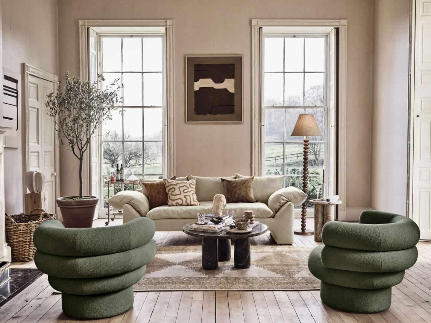 A living room with high ceilings, huge windows and sculptural furniture in green and cream from Soho Home