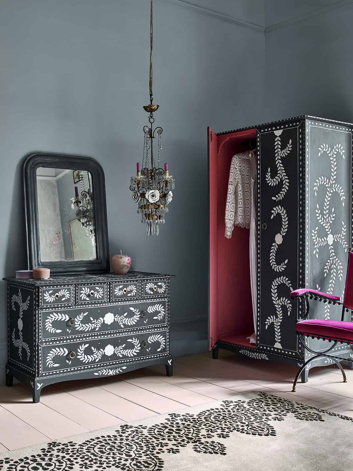 A wardrobe and a chest of drawers that have been painted in black chalk paint by Annie Sloan with white botanical patterns stencilled onto them