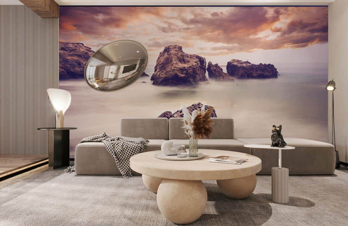 Ever Wallpaper-Wandbild mit dramatischen Felsen und Wolken hinter einem minimalistischen grauen Sofa und einem runden Couchtisch aus Stein