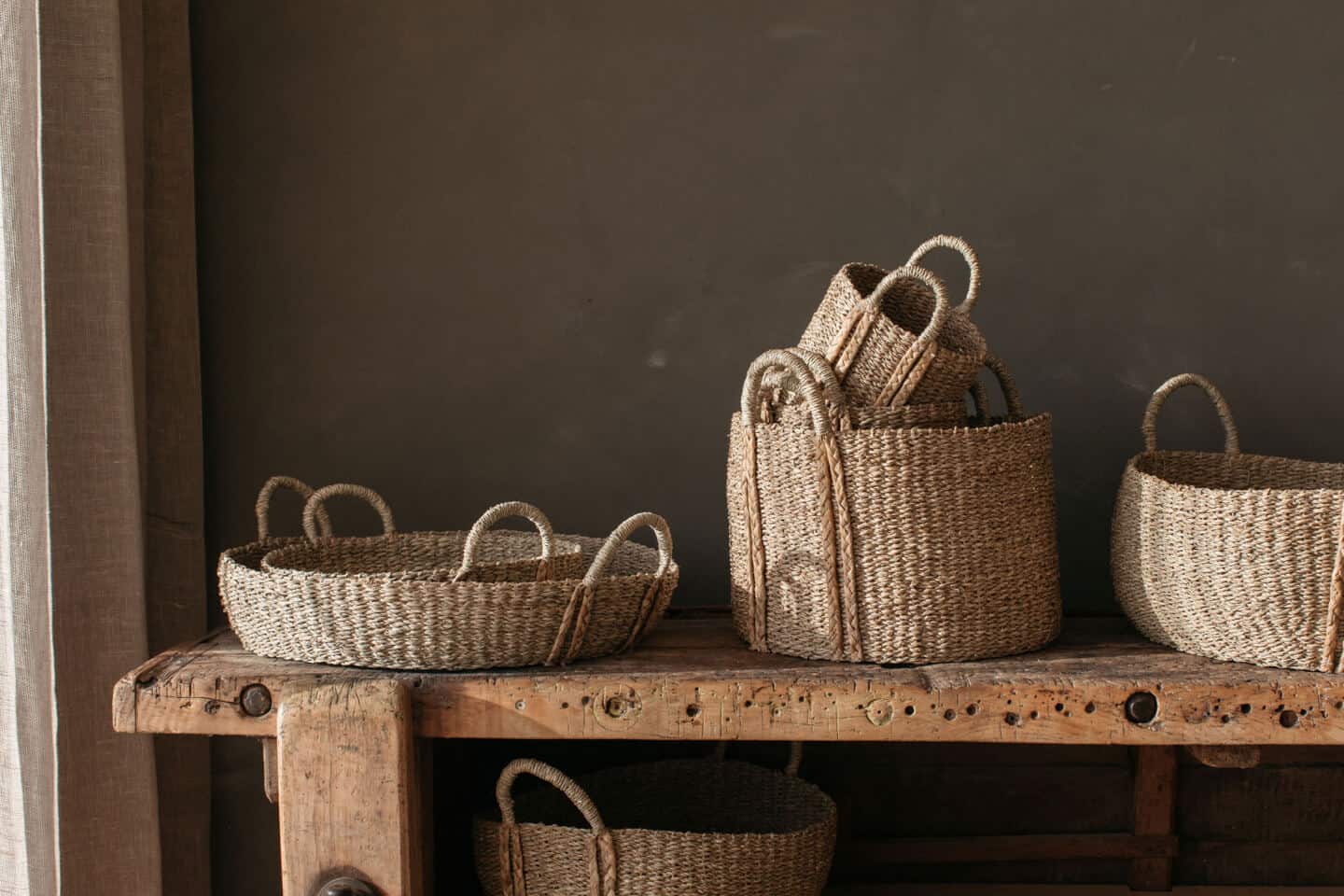 Seagrass baskets sit atop a weathered wooden bench demonstrating the elements of a biophilic home