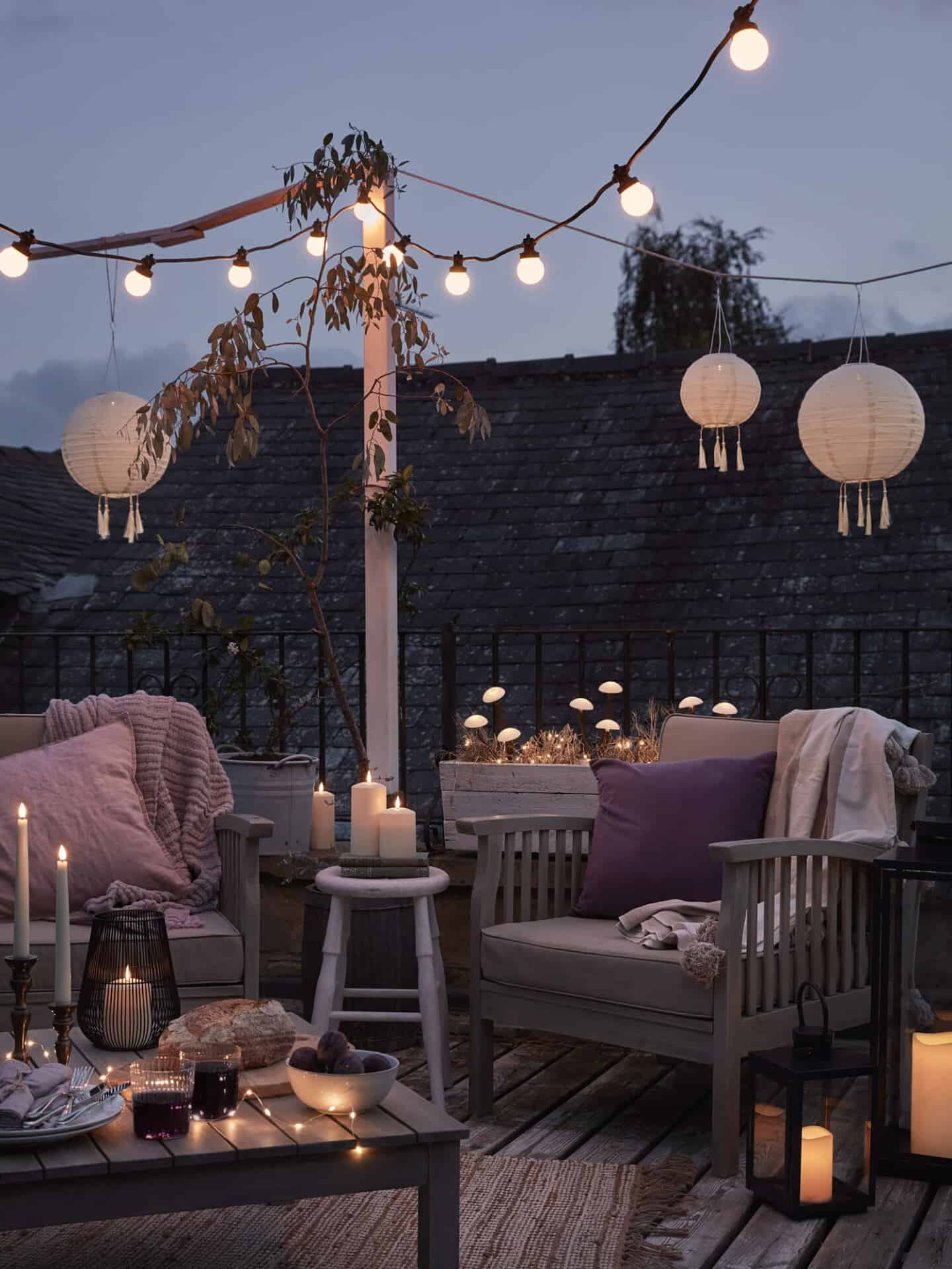 Patio featuring wooden seating, blankets, Candles, Festoon Lights, Mushroom Stake Lights and Solar Lanterns