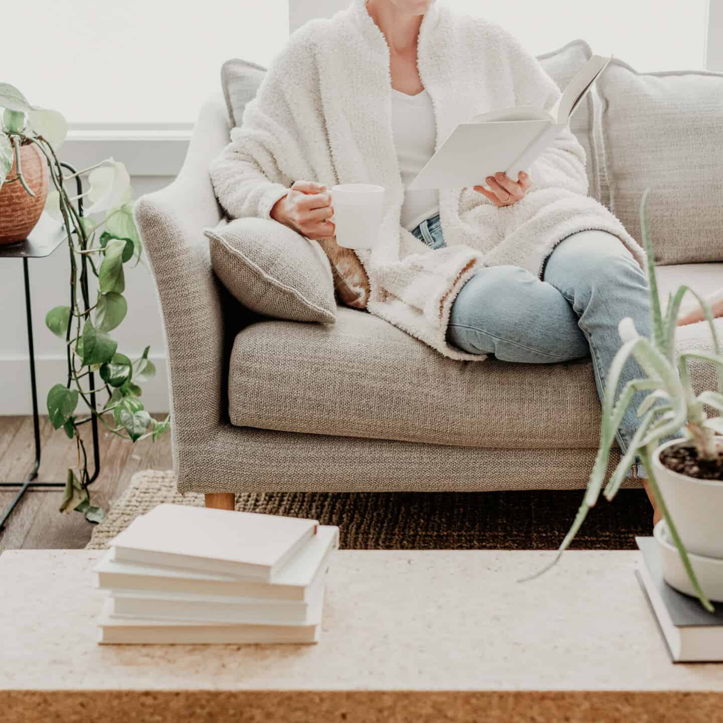 A woman reading books on a sofa