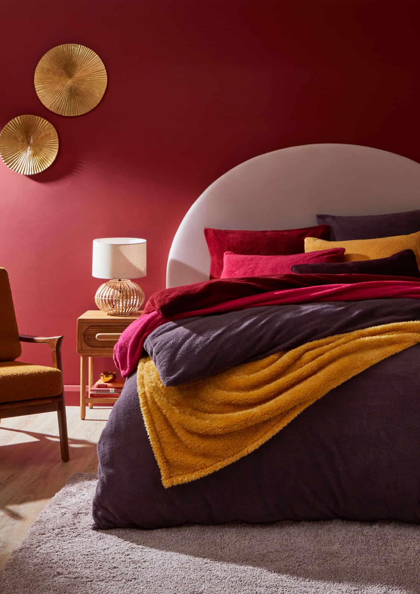 A cosy bedroom with lots of soft teddy bear bedding in purples, deep pinks and ocre yellow