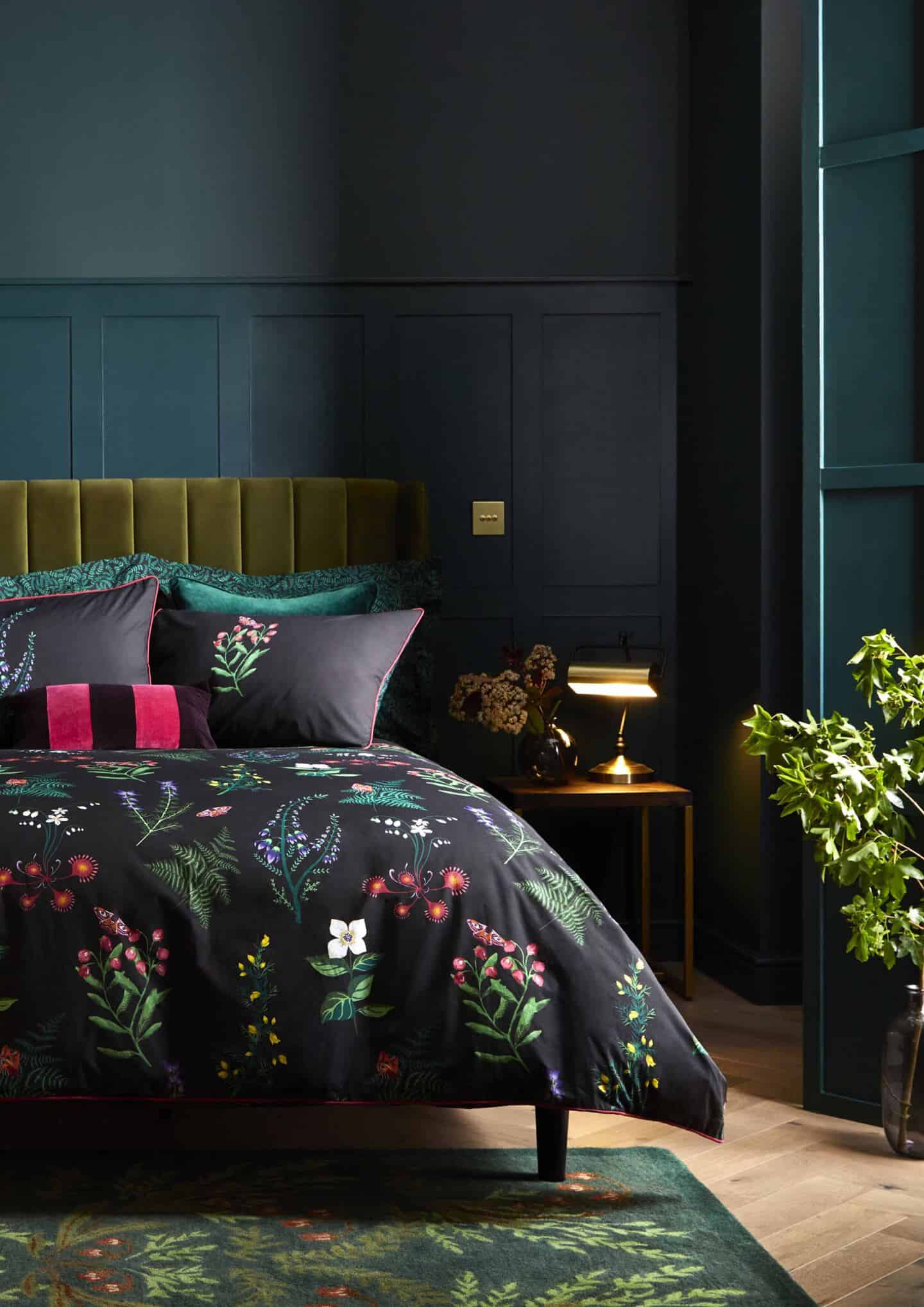 A cosy dark bedroom with luxurious bedding and a soft green rug