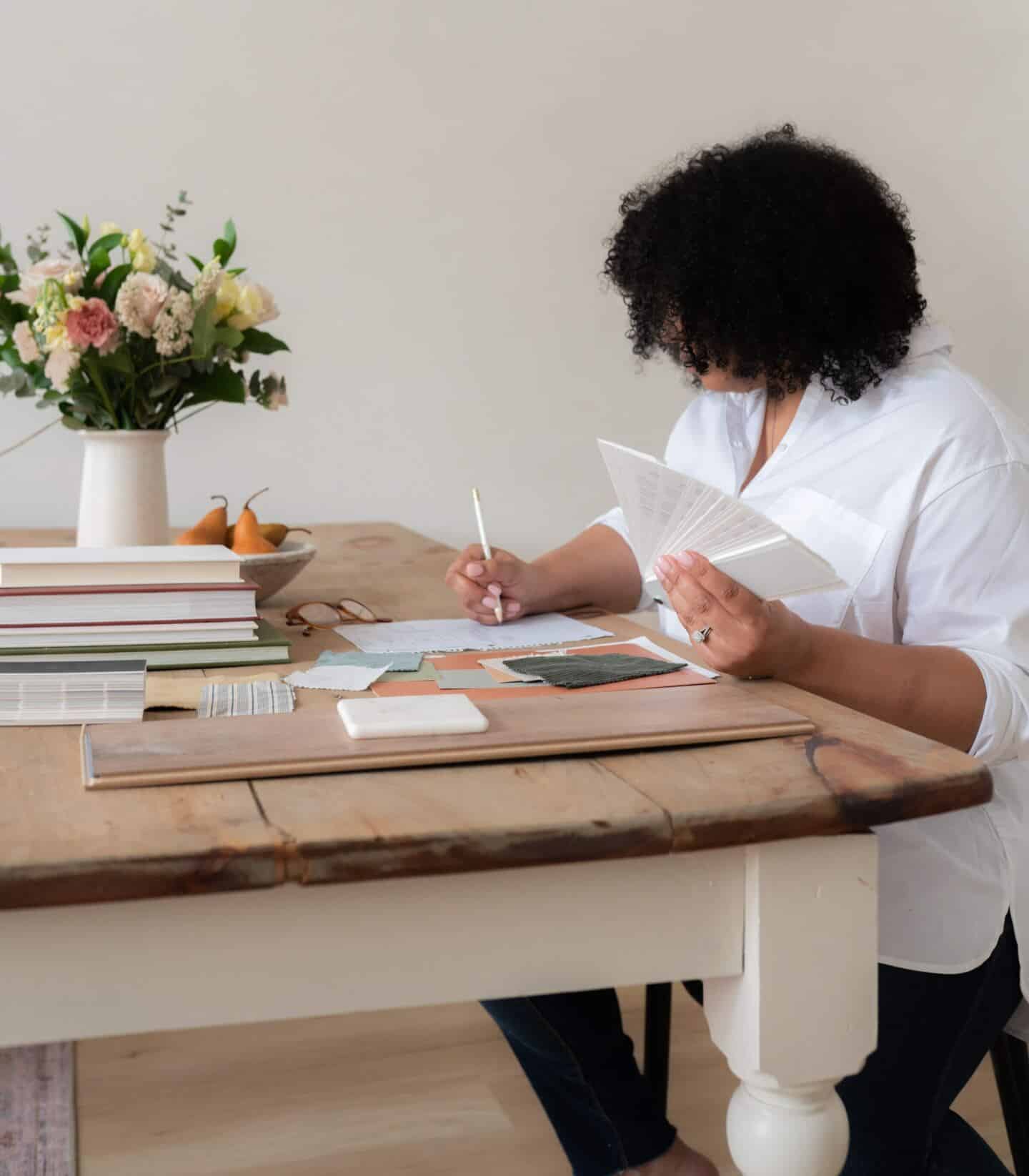 Woman sits at a dining table planning a home makeover project