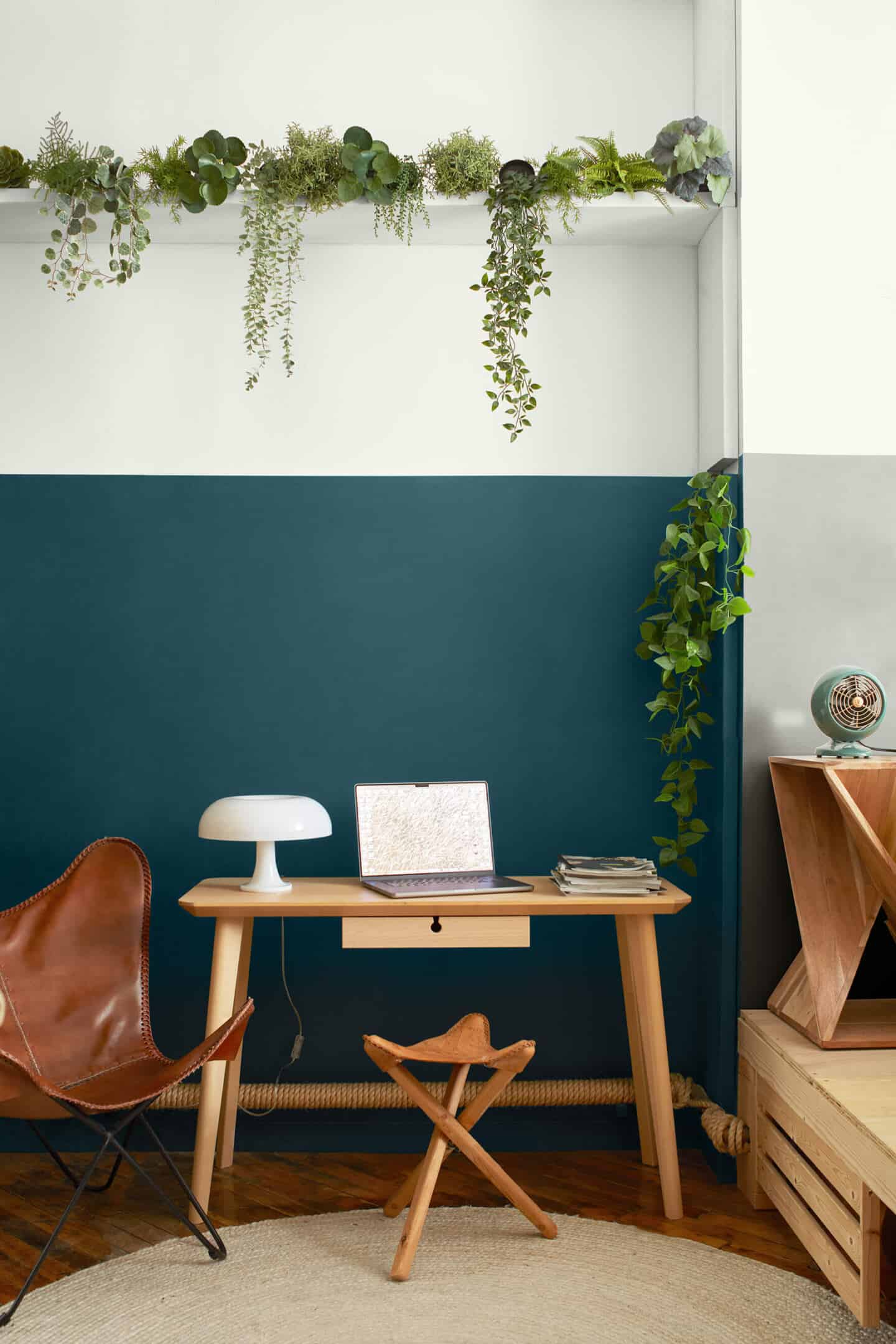 A wooden desk and stool in front of a blue wall in Benjamin Moore paint makes for a productive home office