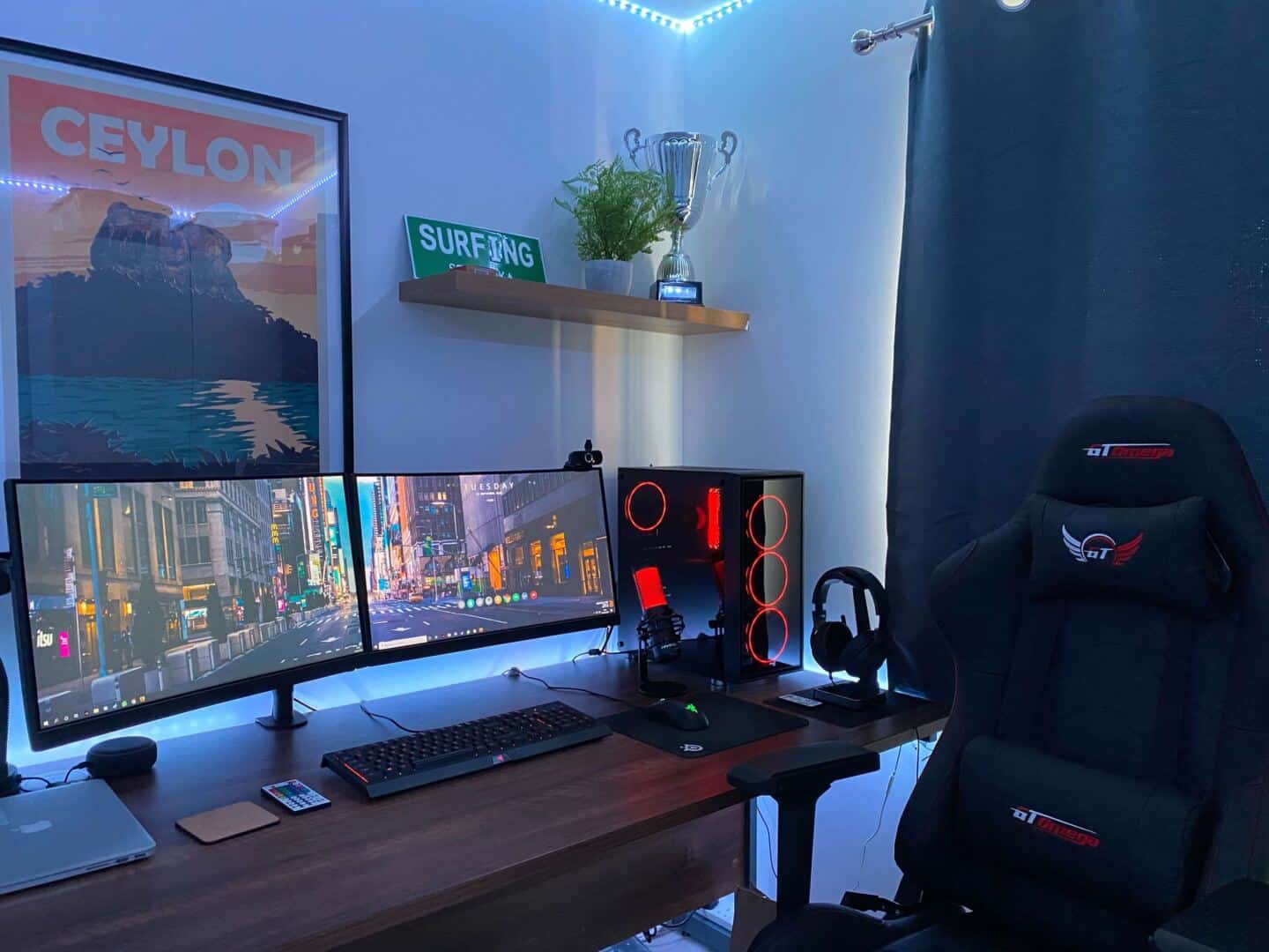 home gaming setup with two screens, a gaming chair and and a pc tower lit up with red lights