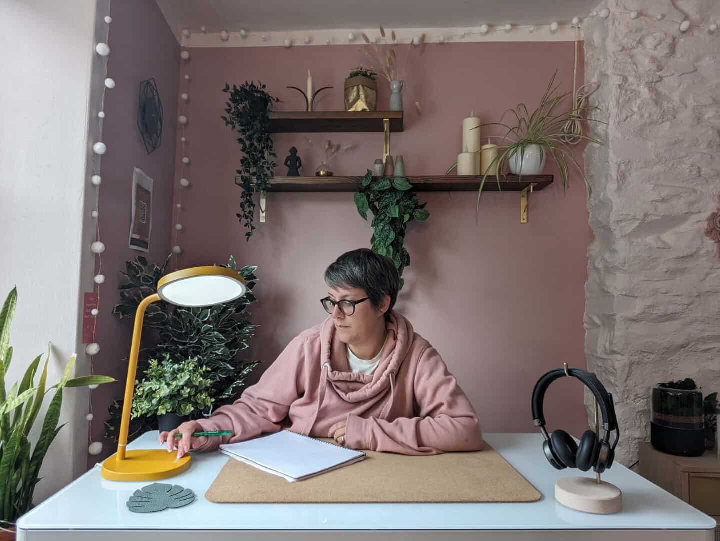 Woman in her 40s sat at a desk writing a review of the Lumie task lamp