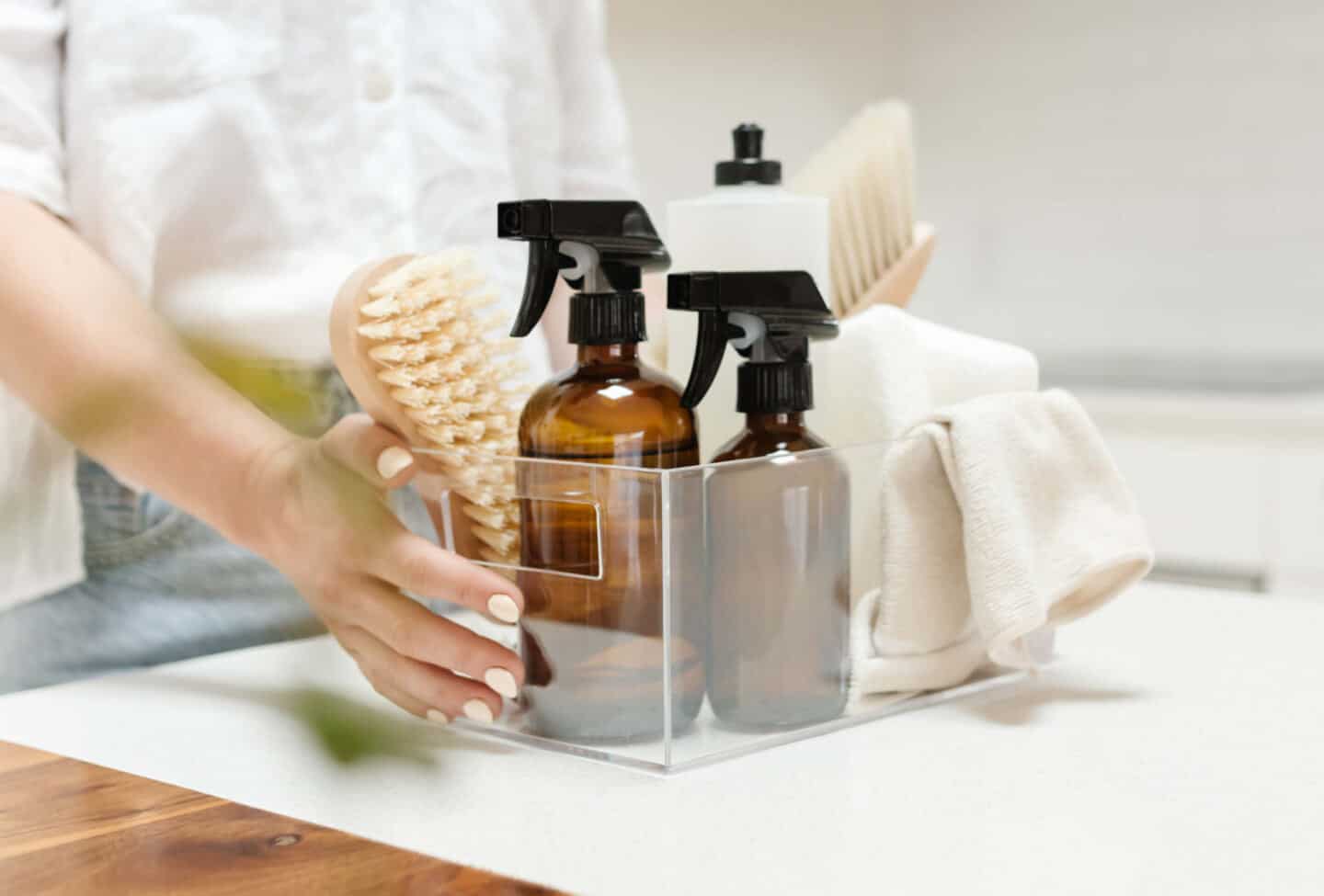 A woman holding a caddy full of cleaning materials