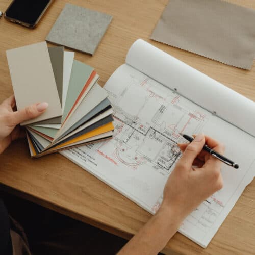 An interior designer holds colour swatches next to a technical drawing on her desk